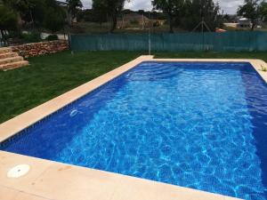 a swimming pool with blue water in a yard at El Retiro de Cervantes in Ossa de Montiel