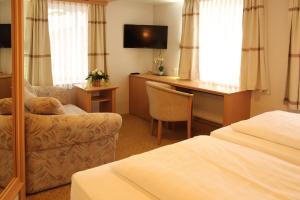 ゼーンデにあるHotel & Restaurant Bei Bakiのベッドと椅子と机があるホテルの部屋