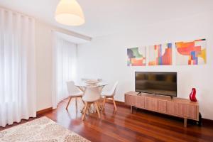 un soggiorno con TV, tavolo e sedie di BmyGuest - Central Garage Apartment a Lisbona