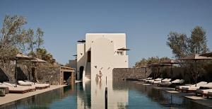 a resort with a pool and chairs and a building at Istoria, a Member of Design Hotels in Perivolos