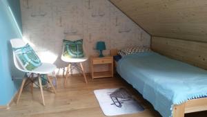 a room with two beds and two chairs in a attic at Apartament nad jeziorem in Wilkasy