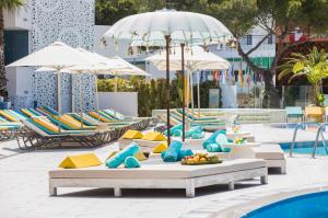 a pool with lounge chairs and umbrellas next to a swimming pool at Sotavento Club Apartments - Adults Only in Magaluf