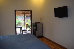 a bedroom with a bed and a television on a wall at Sweetville Home in Sangkhla Buri