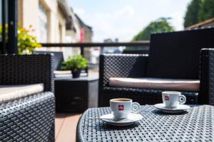 - deux tasses de café assises sur une table sur une terrasse dans l'établissement The Originals City, Hôtel du Château, Pontivy (Inter-Hotel), à Pontivy
