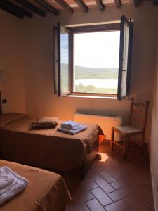 Habitación con 2 camas, silla y ventana en Tenuta La Tabaccaia, en La Pesta