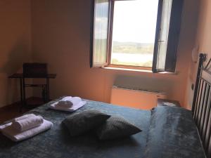 una camera da letto con un letto, asciugamani e una finestra di Tenuta La Tabaccaia a La Pesta