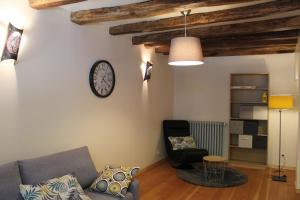 a living room with a couch and a clock on the wall at gîte "la percée des lacs" in Châtillon +1 photo