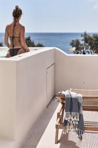 a woman sitting on the ledge of a balcony overlooking the ocean at Istoria, a Member of Design Hotels in Perivolos