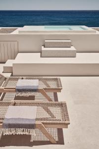 two lounge chairs and stairs on a building with the ocean at Istoria, a Member of Design Hotels in Perivolos