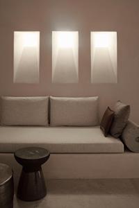 a couch with two lights on the wall at Istoria, a Member of Design Hotels in Perivolos