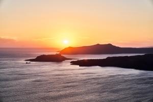 a sunset over the ocean with a mountain in the background at Istoria, a Member of Design Hotels in Perivolos