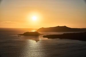a sunset over a body of water with a island at Istoria, a Member of Design Hotels in Perivolos