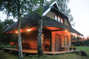 a small log cabin with a porch and a table at Kalniaus-Sodyba in Barkellai