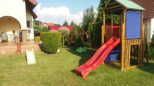 a playground with a red slide in a yard at Pokoje Gościnne u Elżbiety in Sztutowo