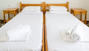 two beds in a room with white sheets and towels at The Boulas Rooms in Megalochori