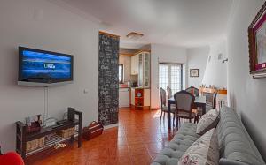 a living room with a couch and a television on a wall at Like-home Boa Onda House-T4-Ericeira center in Ericeira