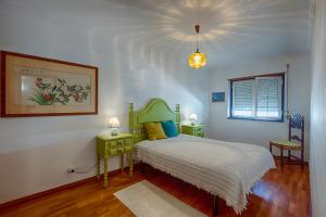 a bedroom with a bed and two tables and a window at Like-home Boa Onda House-T4-Ericeira center in Ericeira