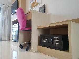 a microwave in a cabinet with a pink chair at Kavin Buri Green Hotel in Udon Thani