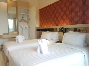 two beds in a hotel room with towels on them at Kavin Buri Green Hotel in Udon Thani
