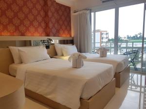 two beds in a hotel room with a balcony at Kavin Buri Green Hotel in Udon Thani