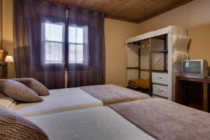 1 Schlafzimmer mit 2 Betten, einem TV und einem Fenster in der Unterkunft Aldea Rural A Cortiña in Pepín