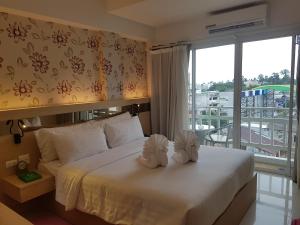 a bedroom with a large white bed with two white towels at Kavin Buri Green Hotel in Udon Thani