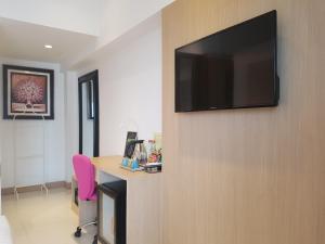 a room with a desk and a television on a wall at Kavin Buri Green Hotel in Udon Thani