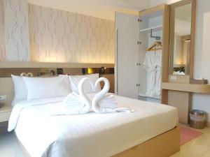 two white swans are sitting on a bed at Kavin Buri Green Hotel in Udon Thani