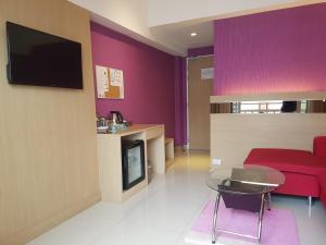 a living room with purple walls and a red couch at Kavin Buri Green Hotel in Udon Thani