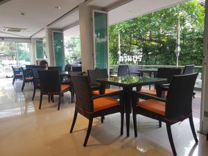 a dining room with tables and chairs and windows at Kavin Buri Green Hotel in Udon Thani