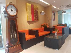 a room with a grandfather clock and orange chairs at Kavin Buri Green Hotel in Udon Thani