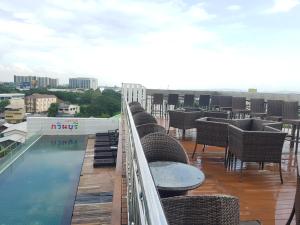 a balcony with chairs and tables and a swimming pool at Kavin Buri Green Hotel in Udon Thani