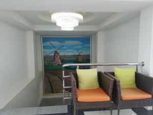 a room with two chairs and a painting of windmills at Kavin Buri Green Hotel in Udon Thani