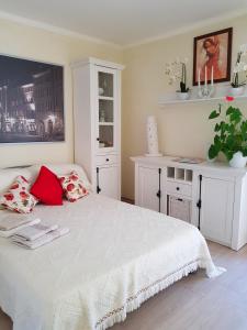 Schlafzimmer mit einem weißen Bett und roten Kissen in der Unterkunft Ferienwohnung Sonnenhaft in Baden-Baden