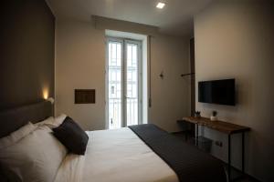 Un dormitorio con una cama blanca y un televisor. en GB Central Station Napoli, en Nápoles