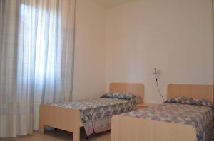 リニャーノ・サッビアドーロにあるVilla Carlottaのベッド2台と窓が備わる小さな客室です。