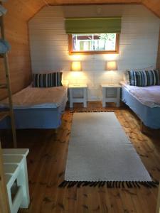 a small room with two beds and a rug at Ollila Rantamökit in Kerimäki