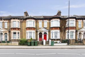 una fila de casas de ladrillo con una puerta roja en Maycourt Gem, en Londres