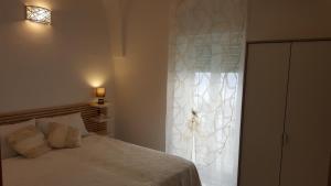 um quarto com uma cama branca e uma janela em La casa di Luvy em Ostuni