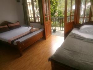 a bedroom with two beds and a balcony at Trinish homestay in Hatton