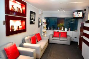 una sala de estar con 2 sofás y almohadas rojas en Hotel Ferre De Ville en Lima