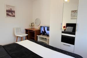 Schlafzimmer mit einem Bett, einem Schreibtisch und einem TV in der Unterkunft Apartman Ana in Otočac
