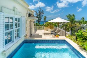 a swimming pool in front of a house with an umbrella at Coral Reef Club in Saint James