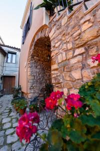 a stone wall with flowers in front of a building at La Finestra Sui Cento Portali in Pignola