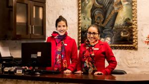 two women standing at a desk with a computer at El Portal De San Lázaro in Arequipa
