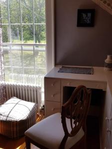 a chair in a room with a desk and a window at Burnbrae Farm & Paradise Inn in Bridgetown