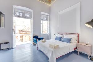 a white bedroom with a large bed with blue pillows at Homey in Ermoupoli