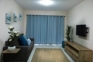 a living room with a couch and a blue curtain at The Living Collective Apartments in Pietermaritzburg
