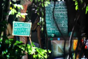 a sign for a music class in front of a woman at Lagarto Na Banana Hostel in Pipa