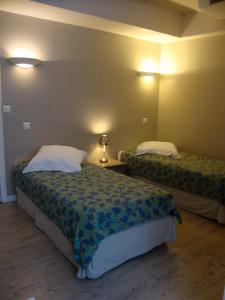 a bedroom with two beds and a lamp on a wall at Hôtel Restaurant de la Place in Saint-Jean-dʼAngély